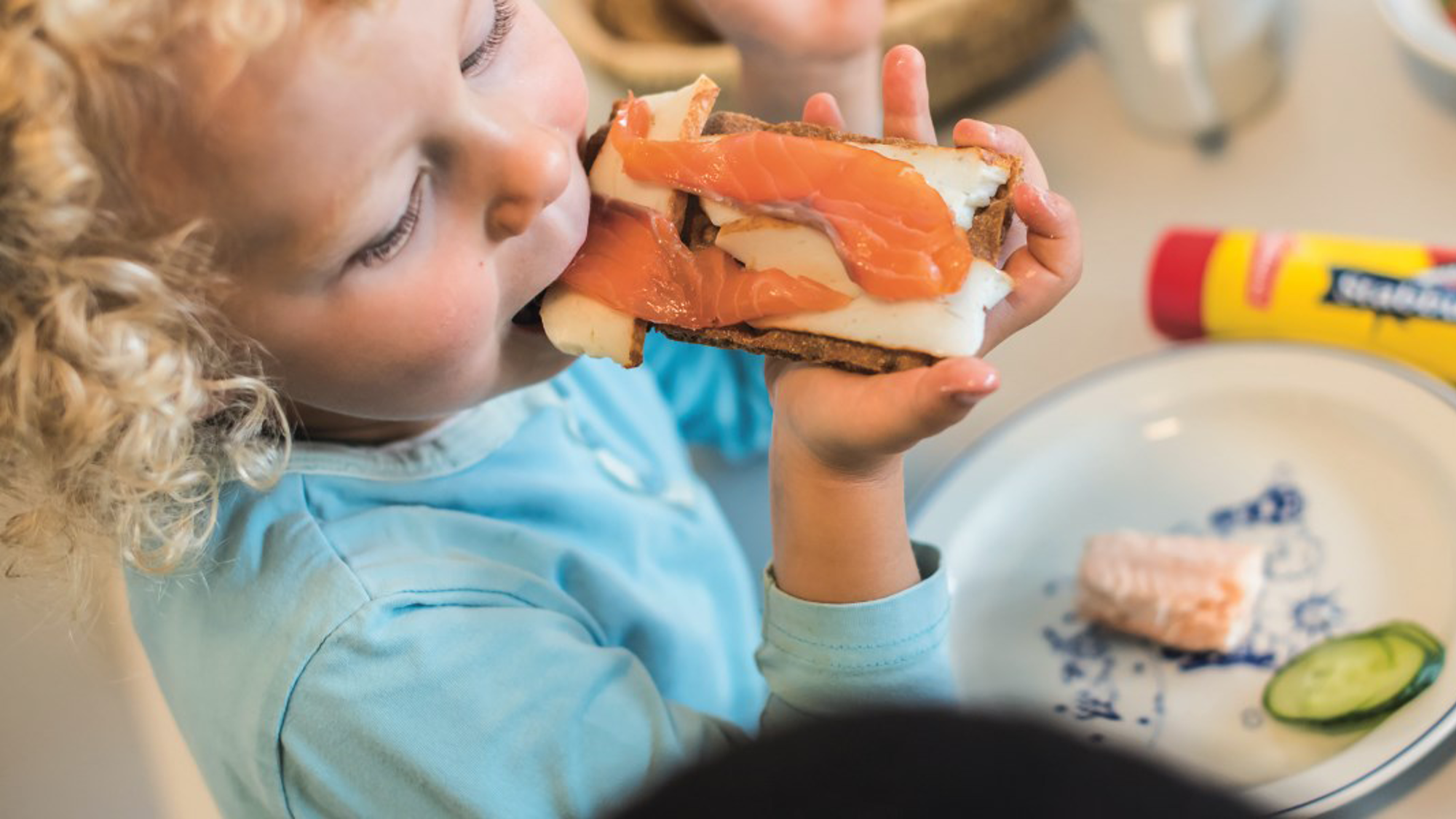 Barn som spiser knekkebrød med fiskepålegg